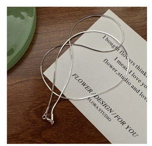 Detail view of high-polish S925 sterling silver flat snake chain with lobster clasp on desk