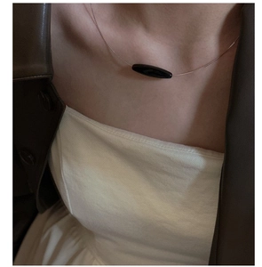 Detail of a minimalist S925 silver necklace with a black oval agate pendant on a female model