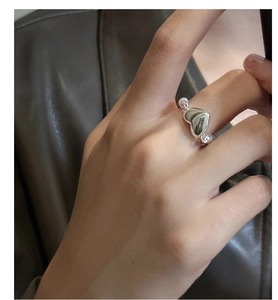 Détail d'une bague coeur en argent avec perles portée à la main sur fond de cuir