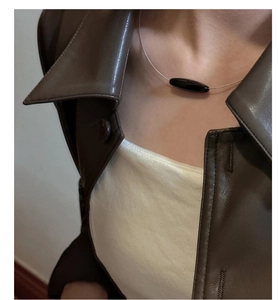 Close-up of minimalist rose gold necklace with oval black agate pendant on model