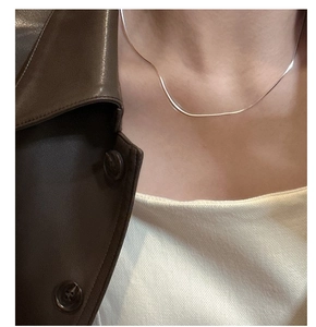 Close-up of minimalist S925 sterling silver herringbone snake chain worn on neck