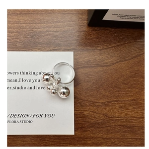 Detailed view of S925 sterling silver open ring featuring polished ball charms on wood
