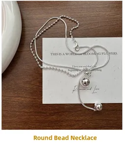 Close-up of double-layer silver beaded necklace with round ball pendants on a paper background