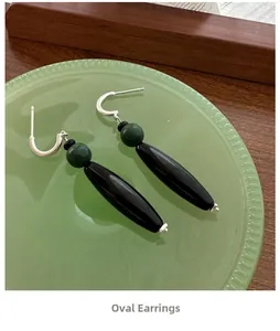 Macro detail of retro S925 silver oval earrings with green beads on a glass plate