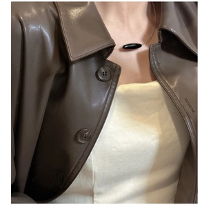 Close-up of a minimalist black agate pendant on a thin silver chain worn by a model