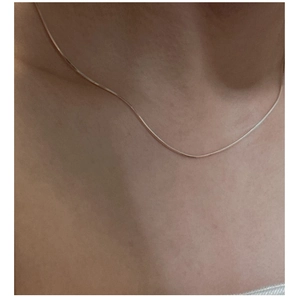 Close-up of minimalist S925 sterling silver square snake chain on woman's collarbone