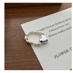 Gros plan détaillé d'une bague en perles avec un pendentif en cœur argenté sur carte