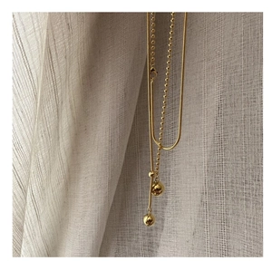 Detail of gold snake chain and bead chain necklace with polished sphere pendants