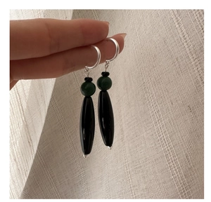 Macro detail of S925 silver earring with green agate bead and black drop pendant
