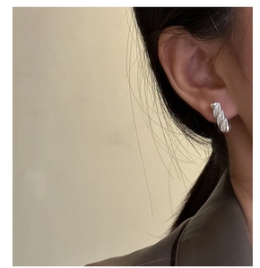 Close-up of a model wearing silver S925 croissant stud earrings with fine textured details