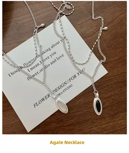 Close-up of double-layer S925 silver necklace with black agate and white shell pendants
