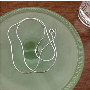 Close-up of minimalist S925 sterling silver square snake chain on a green frosted tray