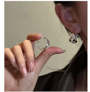 Close-up of S925 sterling silver interlocking hoop earrings shown on a model