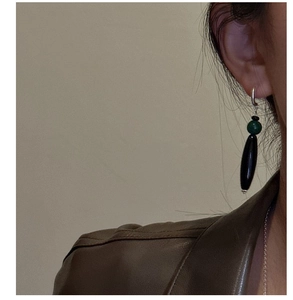 Detail of drop earrings with green bead and black tube on model for retro style