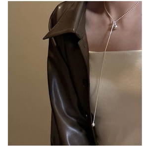 Detailed view of silver S925 adjustable ball pendant necklace on a leather jacket model