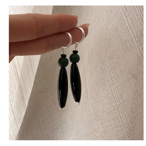 Close-up of S925 silver long drop earrings featuring green and black beads on hand