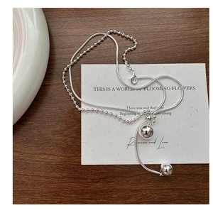 Detail of double-layer silver S925 snake chain necklace with polished metal ball pendants