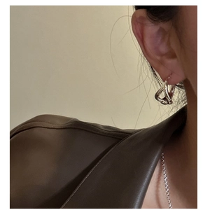 Close-up of a model wearing minimalist silver twisted hoop earrings with a modern design