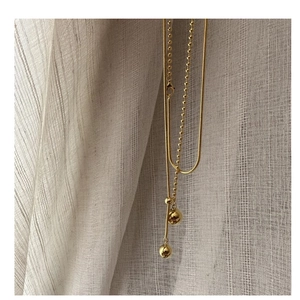 Detail of layered gold beaded and snake chain necklace with polished sphere pendants
