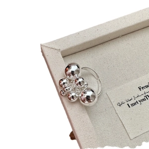 Minimalist S925 sterling silver clustered bead ring with polished finish on linen background