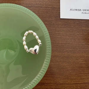 Bague élégante en perles avec pendentif cœur en argent S925 sur un bureau en bois brun