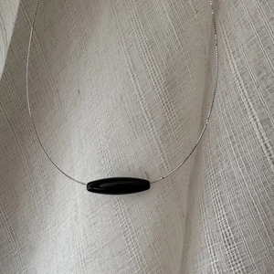 Minimalist S925 silver beaded necklace with a black oval agate pendant on linen cloth