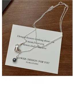Detail of S925 silver heart necklace with grey pearl on an elegant art card