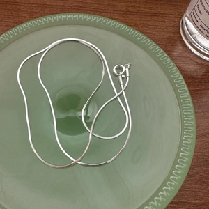 Minimalist S925 sterling silver square snake chain necklace on a green glass plate