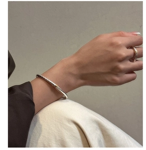 Detail of S925 silver textured ring and bangle set with golden embossed accents on model
