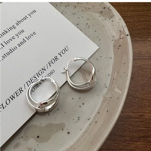 Detail of twisted double-layered S925 sterling silver hoop earrings on a ceramic tray