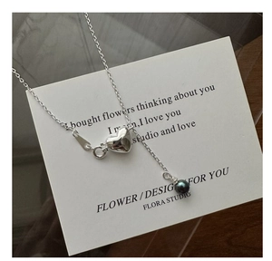 Detail of S925 silver necklace featuring a polished heart charm and a dark lustrous pearl