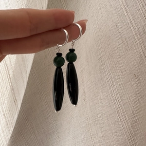 Handheld view of S925 sterling silver drop earrings with green beads and black pendants