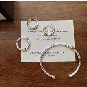 Detailed close-up of woven silver and gold mixed metal jewelry set on a display card