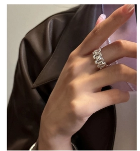Detail of S925 sterling silver wide band ring with geometric textured design on model finger