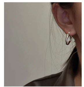 Macro shot of liquid metal earrings in S925 sterling silver worn by a model