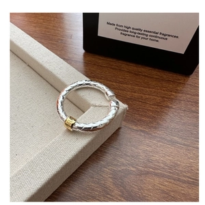 Close-up of S925 sterling silver woven ring with gold-tone cylinder accent and texture