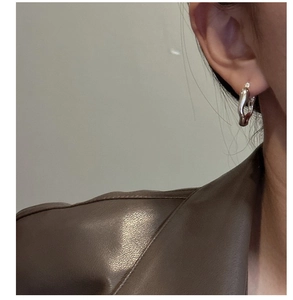 Detail view of liquid sterling silver irregular wave hoop earrings on model