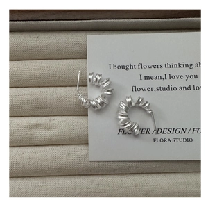 Gros plan de boucles d'oreilles spirales en argent S925 mat sur une boîte à bijoux
