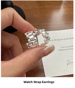 Détail de boucles d'oreilles en argent S925 avec design de bracelet de montre poli