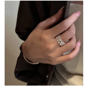 Close-up of wide S925 silver band ring with rectangular zircon stones and metal bracelet