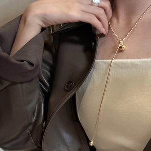 Elegant gold S925 sterling silver Y-shaped ball pendant necklace on brown leather jacket