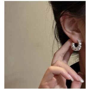Détail de boucles d'oreilles spirales en argent S925 mat sur modèle pour un look chic