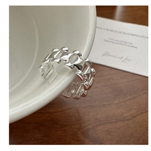 Close-up of industrial watch strap style S925 silver ring on a white ceramic bowl edge