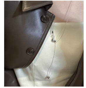 Detail of silver S925 heart pendant necklace on a Y-shaped chain worn with a leather jacket