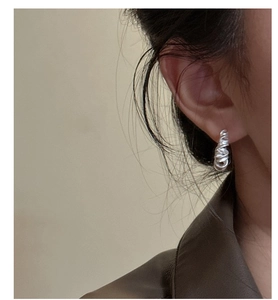 Gros plan d'une boucle d'oreille en argent S925 avec texture mate torsadée sur l'oreille