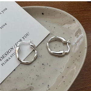 Macro detail of irregular S925 sterling silver liquid earrings on a ceramic dish