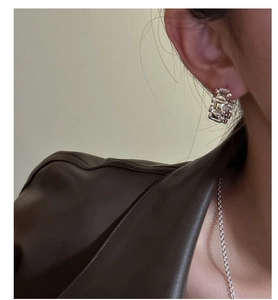 Gros plan de créoles en argent sterling S925 au design tressé portées par un mannequin