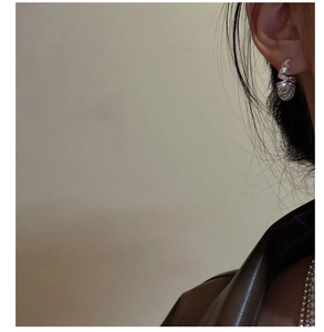 Gros plan de boucles d'oreilles spirales en argent S925 portées par un mannequin élégant