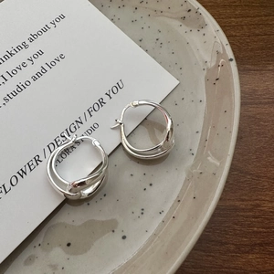 Minimalist S925 sterling silver hollow hoop earrings on a ceramic dish with rustic wooden background