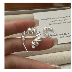 Vue macro de boucles d'oreilles spirales argentées montrant une texture mate et un design épuré